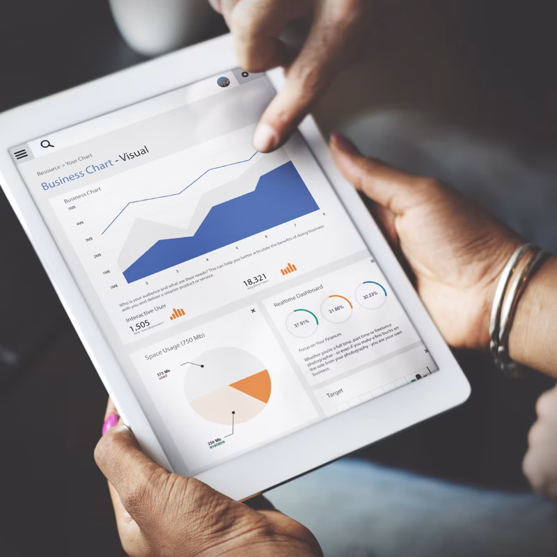 Hands using a tablet displaying business statistics and data charts